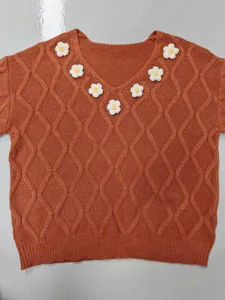 Close-up of the V-neck cable knit sweater with handmade 3D floral crochet details.