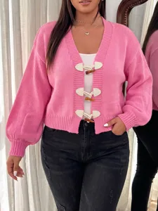 Nahaufnahme des rosa Strickcardigans mit originellen Kneipknöpfen und V-Ausschnitt-Design.