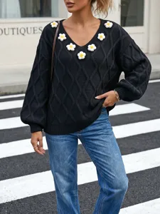 Black cable knit sweater featuring a V-neck, 3D crochet daisy flowers, and cozy lantern sleeves.