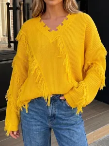 Detail shot of a stylish yellow V-neck fringe sweater paired with classic blue denim jeans.