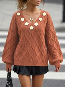 Detailed view of brown cable-knit V-neck sweater with 3D handmade flower appliques and sleeves.