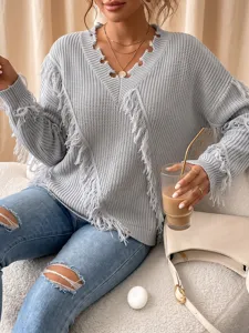 Close-up detail view of the grey knit sweater featuring unique fringe and a deep V-neck style.