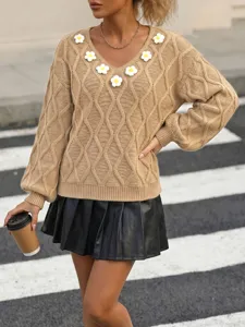 Detail view of a stylish camel cable-knit V-neck sweater featuring 3D crochet flower appliques.