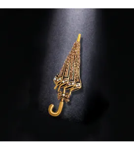 Close-up detail of a vintage golden umbrella brooch with shimmering amber crystals.
