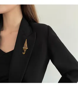 Close-up of a sparkling gold umbrella-shaped crystal brooch pinned on a black blazer lapel