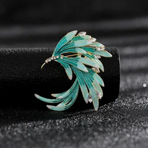 Close-up detail of a vintage wing brooch with green enamel and sparkling rhinestones