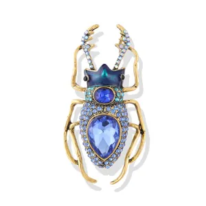 Vintage enamel beetle brooch with blue crystals and a large teardrop gemstone.