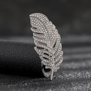 Detailed macro shot of an elegant silver feather brooch encrusted with pavé rhinestones.