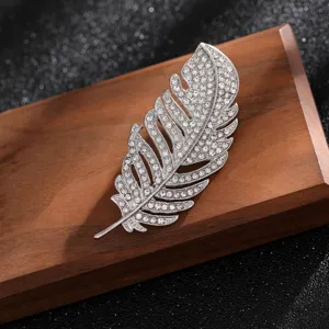 Detailed view of elegant silver feather brooch with shimmering clear rhinestones on wood