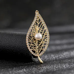 Close-up of elegant golden leaf brooch featuring a central pearl and crystals