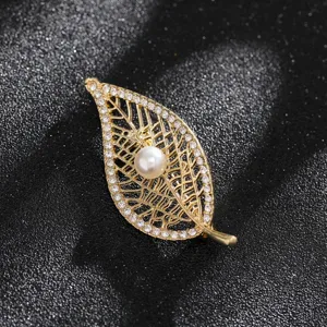 Macro view of a vintage golden leaf brooch with pearl and sparkling rhinestones
