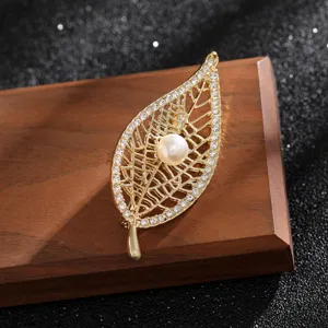 Close-up of elegant gold-tone leaf brooch with pearl and rhinestone details