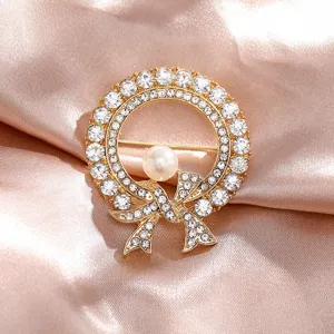 Elegant gold wreath brooch featuring shimmering rhinestones and a central pearl detail
