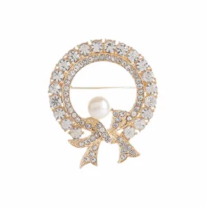 Detailed macro view of an elegant golden wreath brooch with crystal bow and pearl center