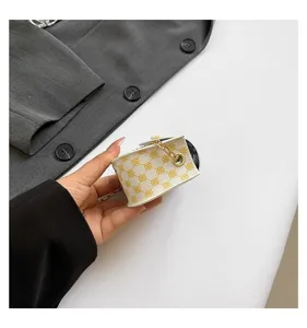 Primer plano de un mini bolso cuadrado blanco con patrón de trébol amarillo