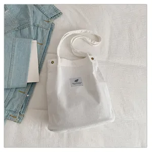 Detalle del bolso tote de pana blanca con textura acanalada y parche minimalista.