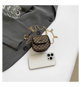 Minibolso retro con cadena y estampado junto a un móvil para comparar el tamaño