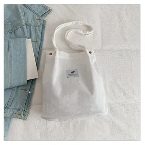 Primer plano de un bolso tote de pana blanca con un parche decorativo de hoja