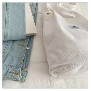 Primer plano de un bolso de pana blanco con textura de canalé fino y etiqueta