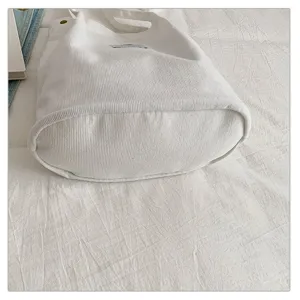 Primer plano que muestra la textura de pana blanca y el diseño de la base del bolso de mano