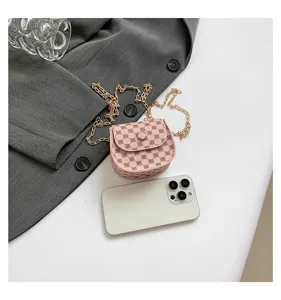 Mini bolso bandolera rosa vintage con cadena dorada comparado con un smartphone