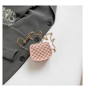 Primer plano del elegante bolso bandolera rosa con monograma y cadena dorada sobre tela gris