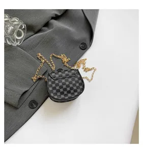 Detalle de bolso bandolera negro retro con patrón geométrico sobre tela gris sofisticada.