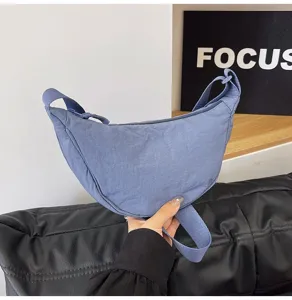 Vista detallada de un elegante bolso de nylon azul con forma de media luna.