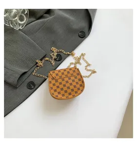 Detalle de bolso de hombro marrón con monograma y correa de cadena dorada.