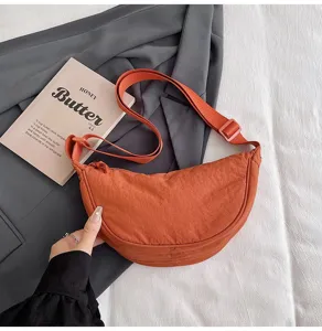 Vista detallada del elegante bolso media luna de nailon naranja para llevar cruzado.