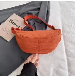 Detalle de un elegante bolso bandolera de nailon naranja terracota con correa ajustable