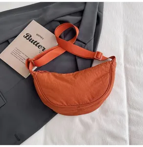 Detalle del bolso bandolera de nailon naranja vibrante con forma de media luna chic.