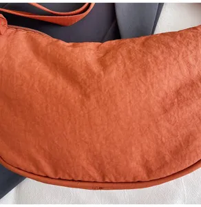 Primer plano de tela de nailon naranja texturizada en un bolso de hombro tipo media luna