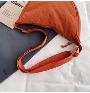 Vista detallada del moderno bolso bandolera de nailon naranja con correa ajustable