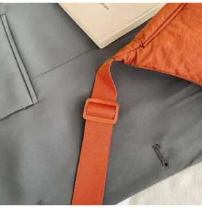 Primer plano detallado de un bolso bandolera de nailon naranja con correa ajustable