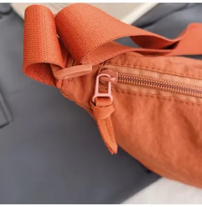 Primer plano de la cremallera y la correa de un bolso bandolera de nailon naranja.