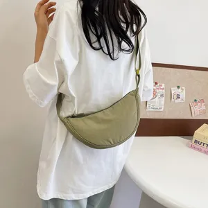 Bolso bandolera casual de nailon verde oliva llevado por una modelo, estilo mínimo