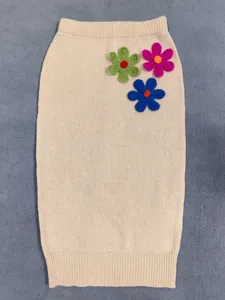 Beige knit skirt detail showcasing vibrant colorful 3D floral crochet appliques and fine texture.