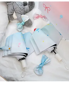 Detail shot of the cute gradient folding umbrella showing pastel colors and bow design.