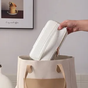 Portable white textured jewelry travel case being placed into a tote bag