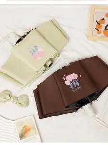 Detail shot of folded mint green and brown tulip umbrellas on a white fabric background