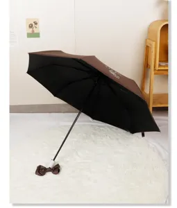 Detail view of an open brown automatic umbrella with a cute cartoon dog and bow handle