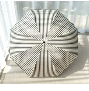 Detailed view of black and white striped folding sun umbrella, excellent UV protection for outdoor use.
