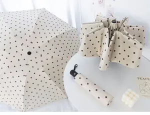 Drei beige gepunktete Automatik-Regenschirme in offenem, gefaltetem und kompaktem Zustand