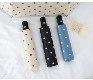 Drei elegante Automatik-Taschenschirme mit Punktmuster in Creme, Schwarz und Blau.