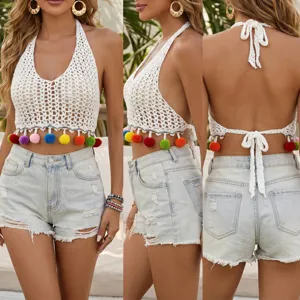 White crochet halter crop top with colorful pom pom fringe paired with denim shorts.