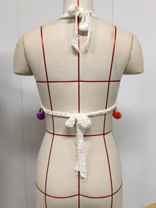 Crochet bikini top back view detail, white halter beachwear with colorful pom-pom accents.
