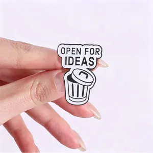 Macro shot of white and black enamel badge featuring Open For Ideas text design