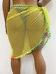 Damen gelber Häkelstrand Sarong Rock mit bunten Bommel Quasten für den Sommerurlaub.