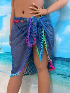 Detailansicht des blauen Häkel-Strand-Überziehrs mit bunten Quastenverzierungen.